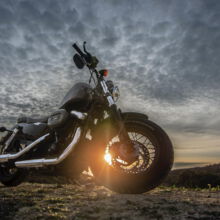 Motorrad aus Froschperspektive mit graubewölkten Hintergrund und einzelnen Sonnenstrahlen