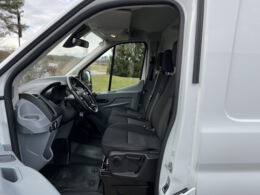 Blick durch geoeffnete Fahrertuer in einen Ford Transit Transporter